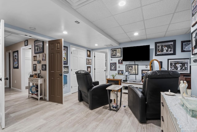 living room featuring baseboards, recessed lighting, light wood finished floors, and a drop ceiling