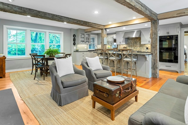 living room featuring recessed lighting, beam ceiling, light wood-style floors, and baseboards