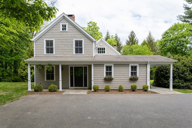 view of front of house featuring a chimney, a porch, and roof with shingles
