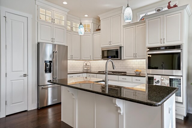 kitchen featuring dark wood-type flooring, an island with sink, white cabinets, and stainless steel appliances