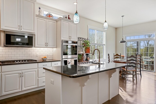 kitchen with plenty of natural light, a sink, appliances with stainless steel finishes, and dark wood-style floors
