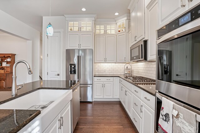 kitchen with dark wood-style flooring, pendant lighting, a sink, white cabinets, and stainless steel appliances