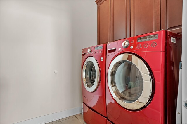 washroom with baseboards, light tile patterned flooring, cabinet space, and washer and dryer