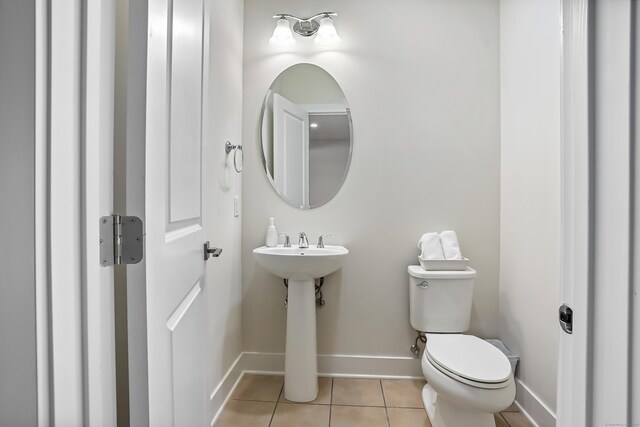 bathroom featuring baseboards, tile patterned flooring, and toilet