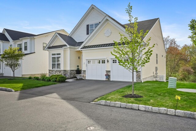 view of front of property with a standing seam roof, driveway, a front yard, central AC unit, and stone siding