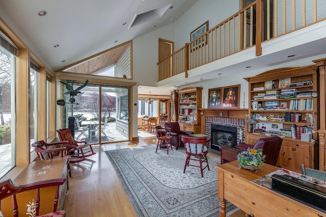 living area featuring high vaulted ceiling, a brick fireplace, and hardwood / wood-style floors