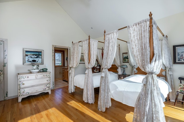 bedroom featuring baseboards, high vaulted ceiling, and wood finished floors