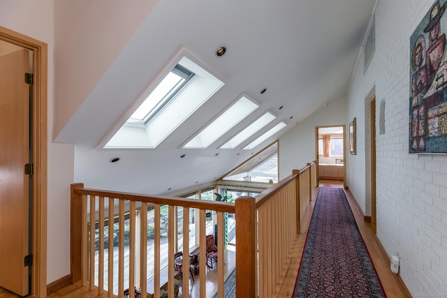 hall featuring visible vents, light wood finished floors, and vaulted ceiling with skylight