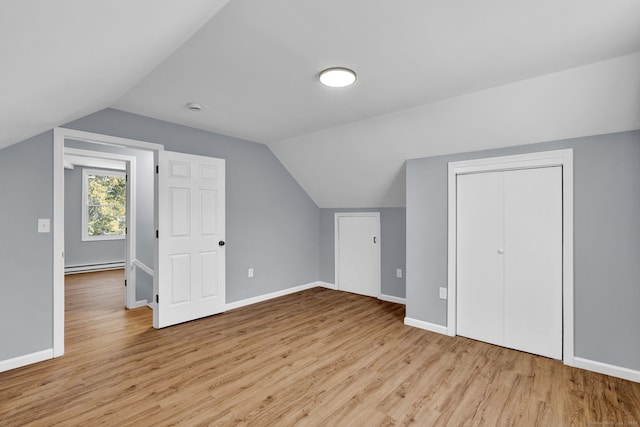 additional living space with baseboard heating, vaulted ceiling, wood finished floors, and baseboards