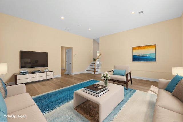 living room featuring recessed lighting, baseboards, wood finished floors, and stairway