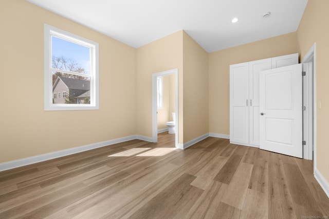 unfurnished bedroom with baseboards, multiple windows, and light wood-type flooring