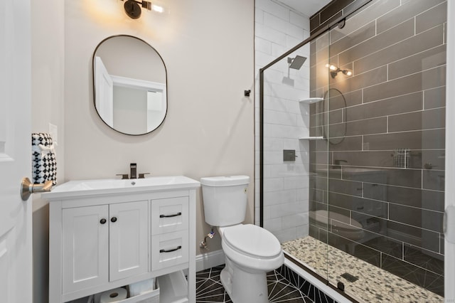 bathroom with a stall shower, tile patterned floors, vanity, baseboards, and toilet