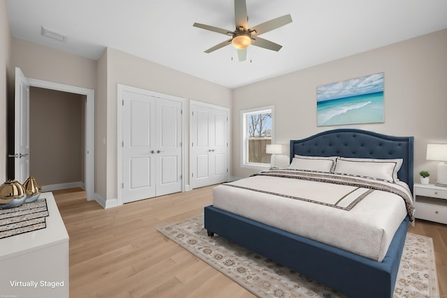 bedroom with multiple closets, baseboards, light wood-type flooring, and visible vents