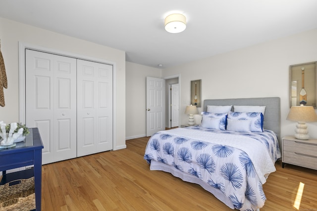 bedroom with baseboards, light wood-style flooring, and a closet