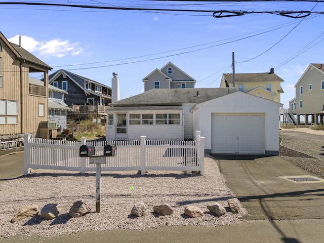 view of front of property with a detached garage, driveway, and fence private yard