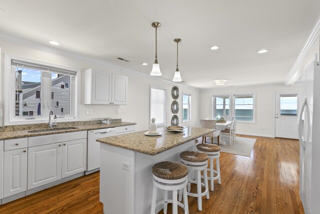 kitchen with a sink, white appliances, visible vents, and wood finished floors