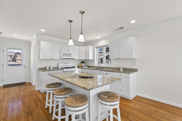 kitchen with white appliances, plenty of natural light, a breakfast bar area, and a sink