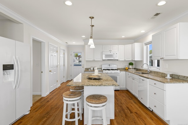 kitchen with ornamental molding, white appliances, visible vents, and a sink