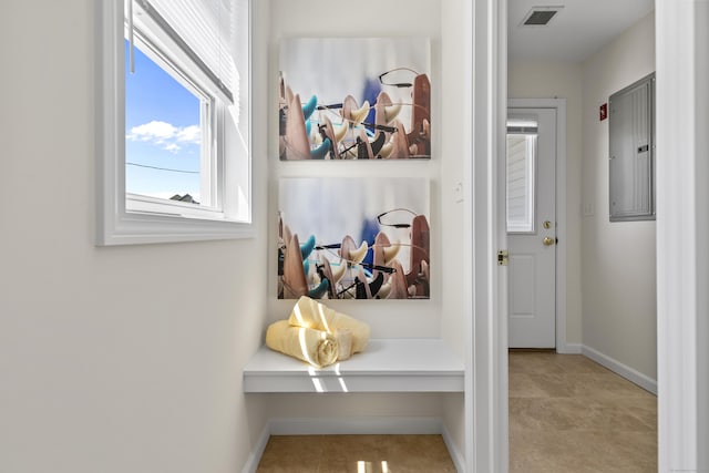 corridor featuring baseboards, tile patterned floors, visible vents, and electric panel