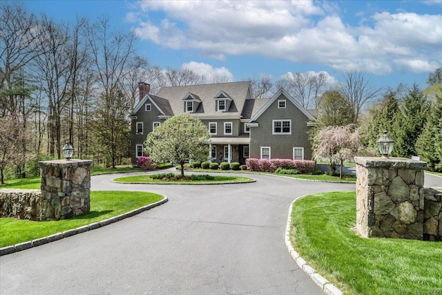 view of front facade featuring a chimney and curved driveway