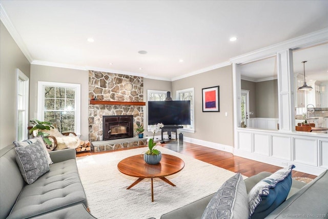 living area featuring a fireplace, wood finished floors, recessed lighting, and ornamental molding