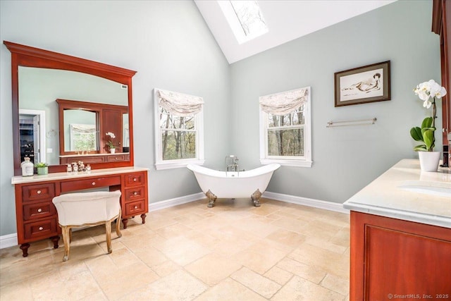 bathroom with a skylight, high vaulted ceiling, vanity, and baseboards