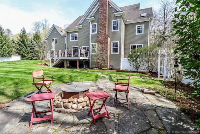 rear view of property with a wooden deck, stairway, a patio area, an outdoor fire pit, and a yard