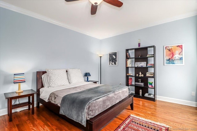 bedroom with wood finished floors, ornamental molding, and baseboards