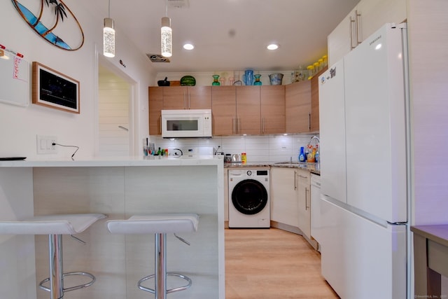 53 E Broadway Unit D, Milford, CT 06460 - kitchen featuring a breakfast bar area, light wood-style flooring, washer / clothes dryer, a sink, and white appliances