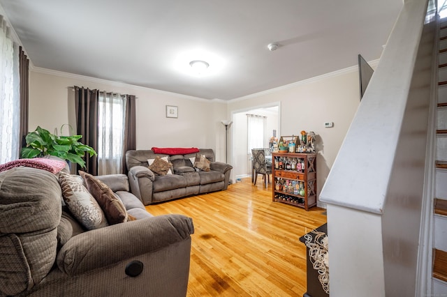 living area with ornamental molding and light wood-style flooring