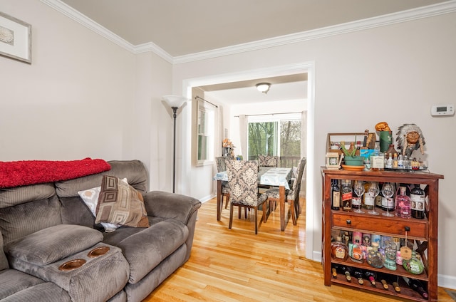 living room with light wood-style floors, crown molding, and baseboards