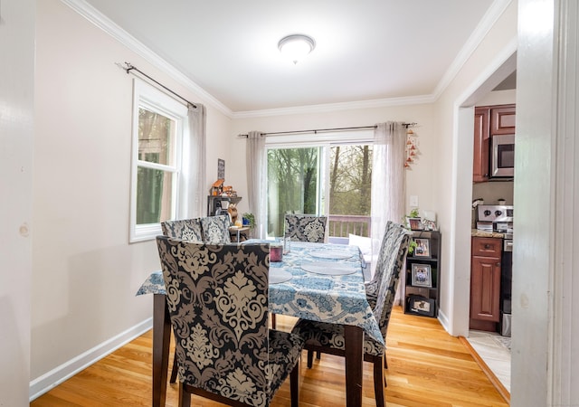 dining area featuring light wood-style floors, crown molding, and baseboards
