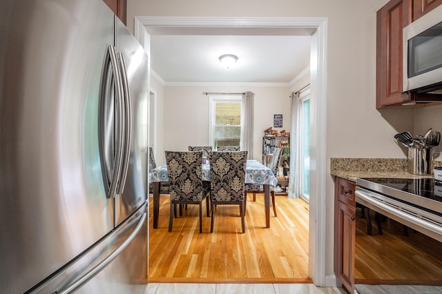 kitchen featuring light wood-type flooring, appliances with stainless steel finishes, crown molding, and light stone counters
