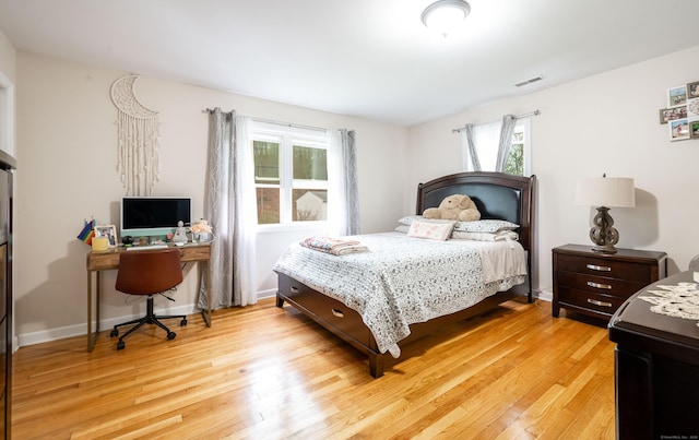 bedroom featuring light wood-style floors, visible vents, and multiple windows