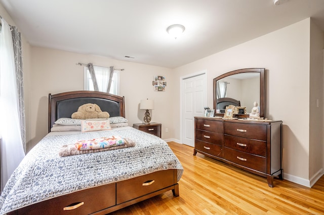 bedroom with light wood-style floors, visible vents, and baseboards