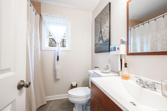bathroom featuring toilet, vanity, and baseboards