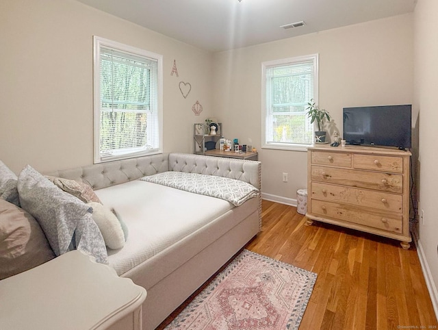 bedroom featuring baseboards, visible vents, multiple windows, and light wood-style flooring