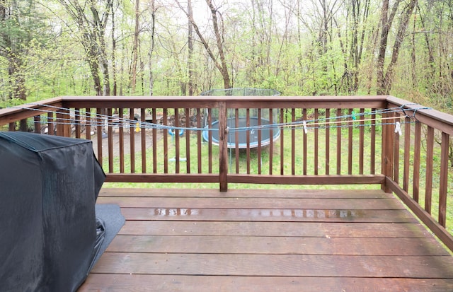 wooden deck with area for grilling, a yard, a fenced backyard, and a view of trees