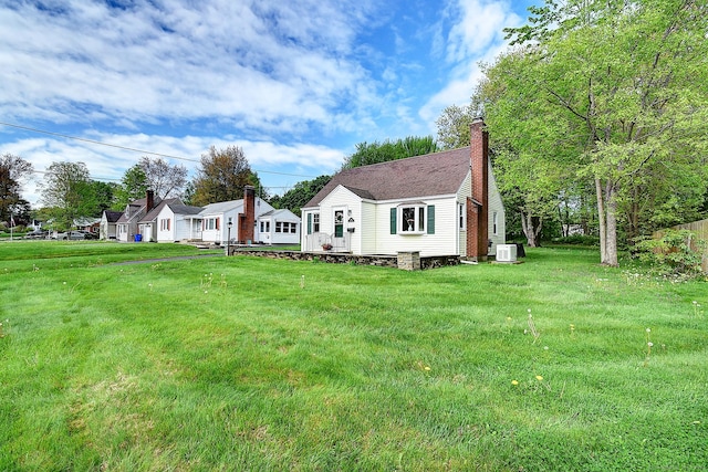 view of front of house with a front yard, a chimney, and ac unit