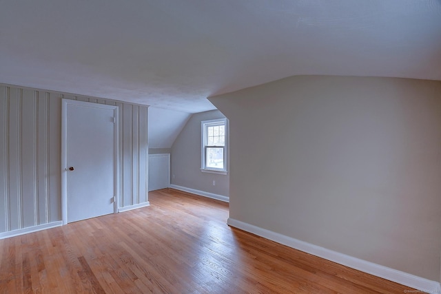 bonus room with baseboards, light wood-style floors, and vaulted ceiling