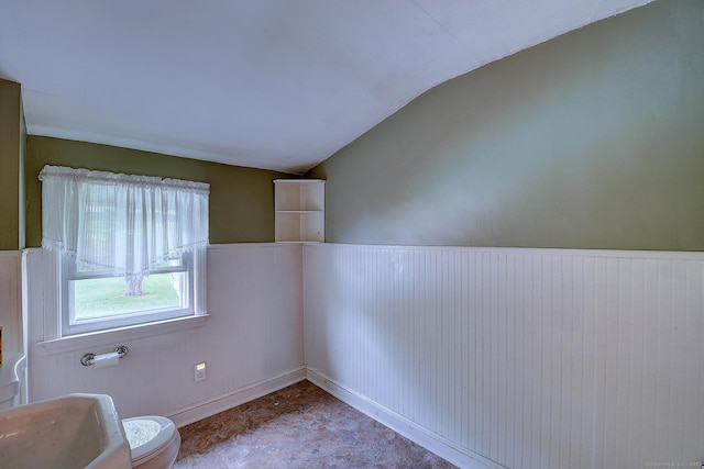 spare room with vaulted ceiling and a wainscoted wall