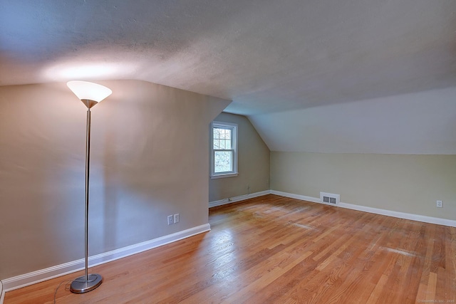 bonus room featuring lofted ceiling, wood finished floors, and baseboards
