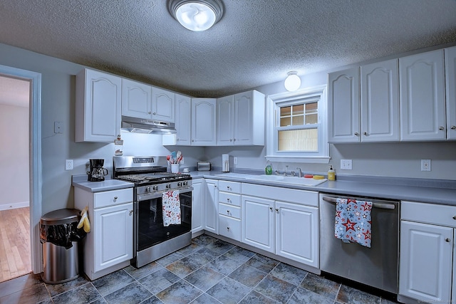 kitchen featuring stainless steel appliances, under cabinet range hood, white cabinets, and a textured ceiling
