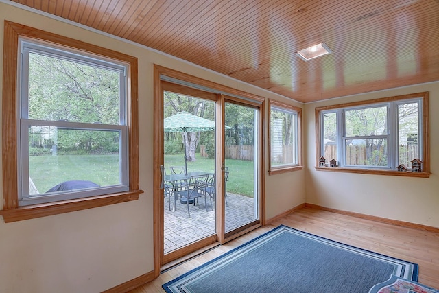doorway with plenty of natural light, baseboards, light wood-style floors, and wood ceiling