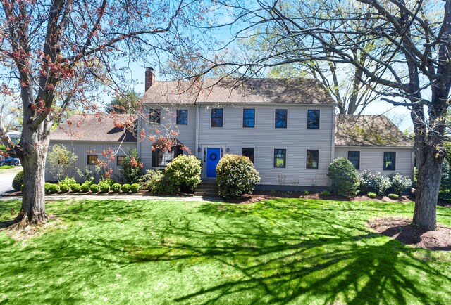 colonial inspired home with a chimney and a front yard