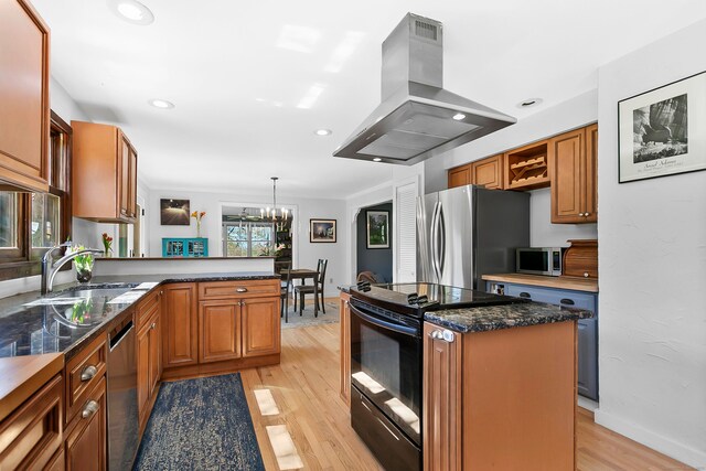 kitchen with appliances with stainless steel finishes, a sink, a chandelier, a peninsula, and island range hood