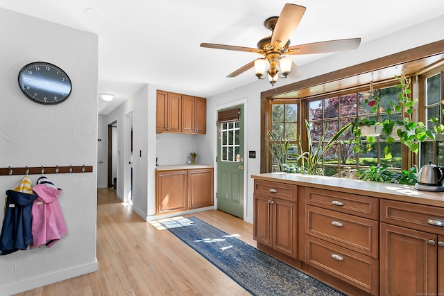 kitchen featuring light countertops, brown cabinetry, a ceiling fan, and light wood finished floors