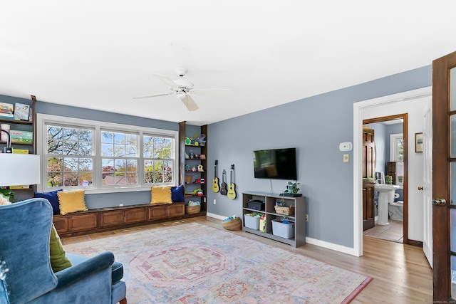 living room with ceiling fan, baseboards, and light wood-style floors