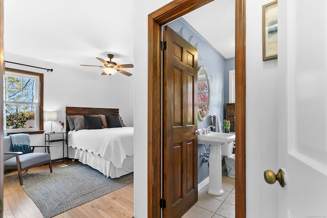 bedroom with crown molding, light wood-style floors, and ceiling fan