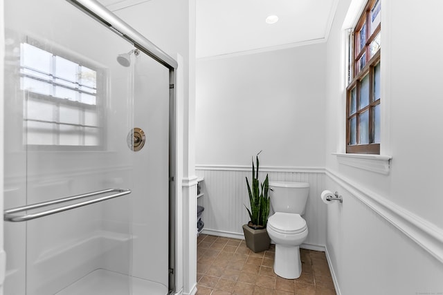 full bathroom featuring wainscoting, a stall shower, and toilet